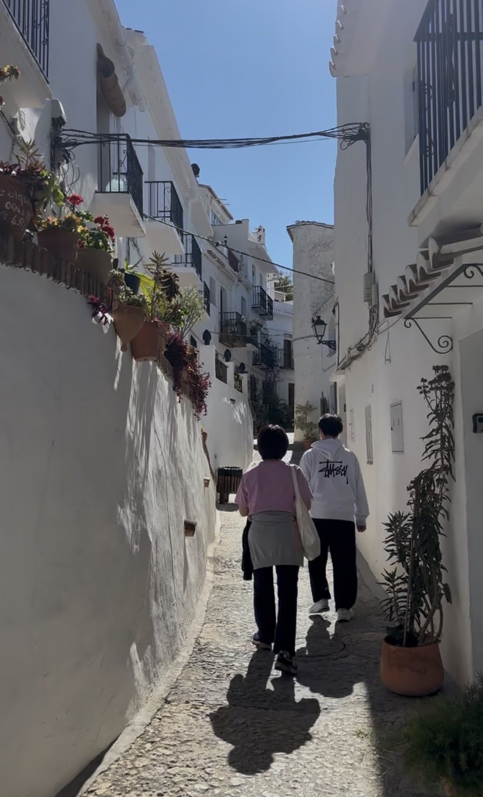 Dos personas caminando por una calle blanca de un pueblo de Málaga