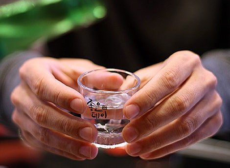 Manos recibiendo un vaso de soju con las dos manos
