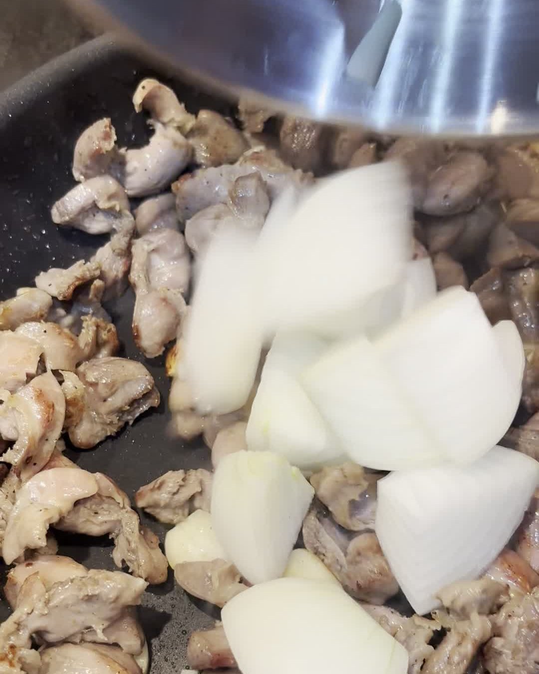 Añadiendo la cebolla a las mollejas doradas en la sartén